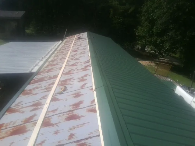 Old rusted panels beside newly installed green metal roofing — Wind Damage Roof Repair by Roofing Brothers in Shoshone