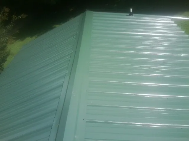 New green metal panels meeting at the ridge of a roof — Flat Roof Repair work by our crew in Shoshone