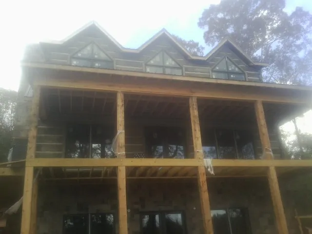 Dormers and porch framing on a large log home under construction — Roof Coating work by our crew in Shoshone
