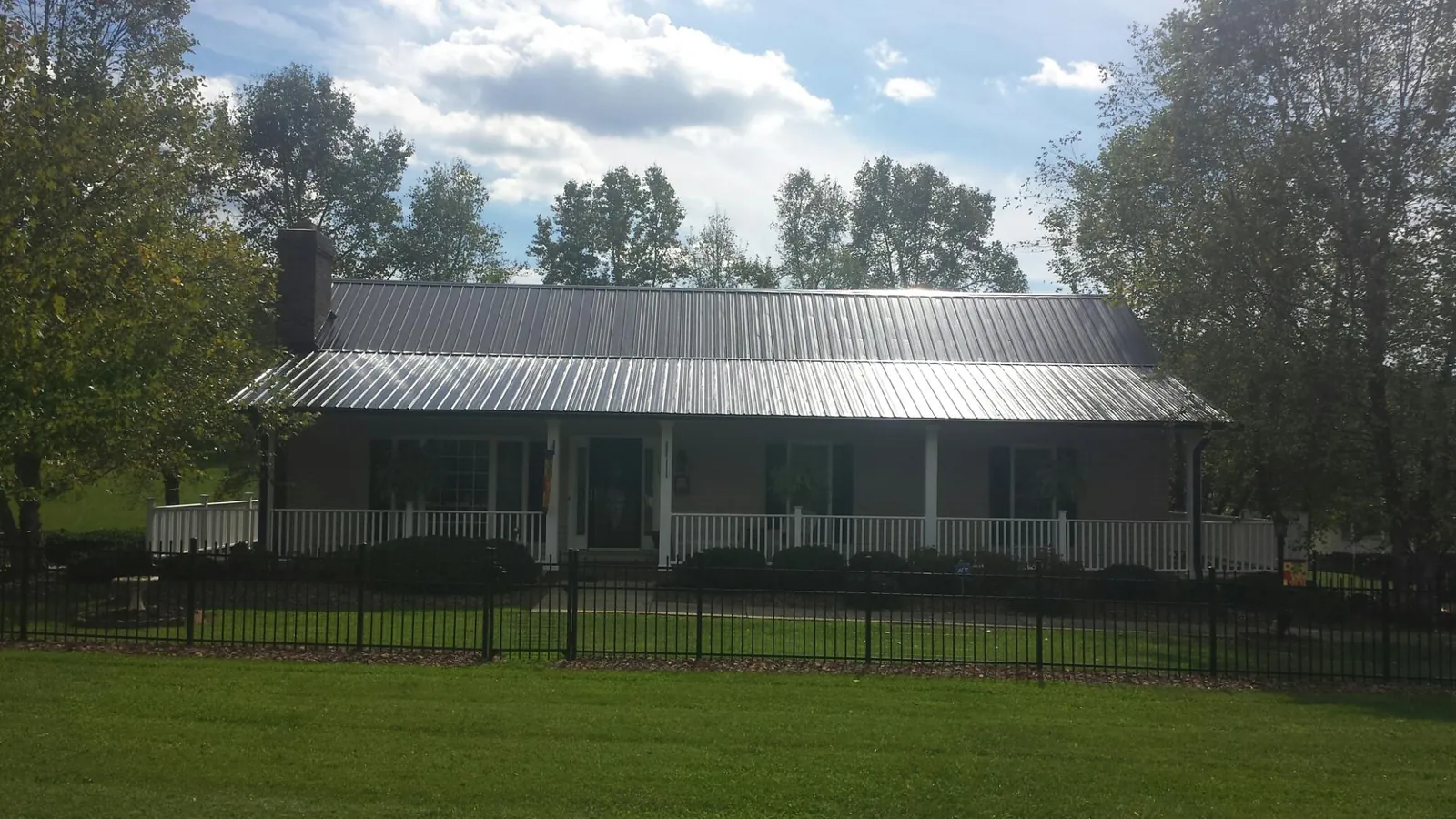 Gray metal roof on a brick ranch with a full width front porch — Gutter Guard Installation work by our crew in Shoshone