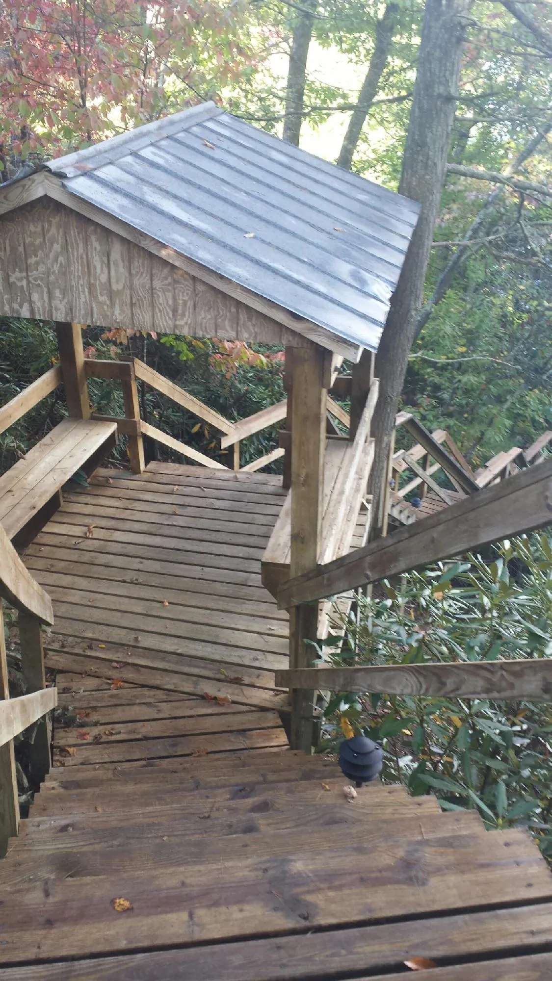 Metal roofed shelter over wooden steps on a wooded walkway — Skylight Repair & Installation work by our crew in Shoshone