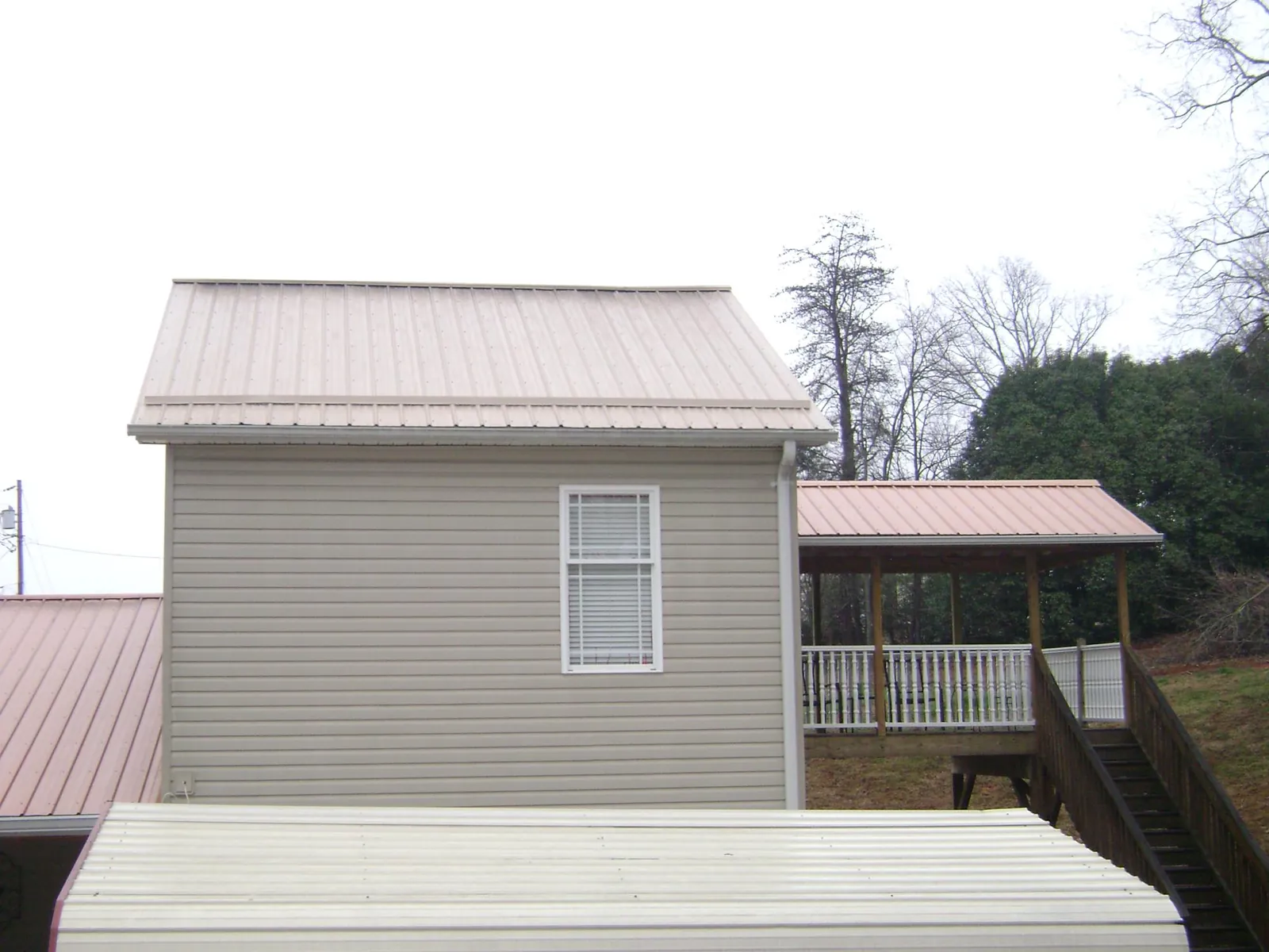 Tan metal roofs on a two story addition and attached porch, from a Roof Replacement job in Shoshone