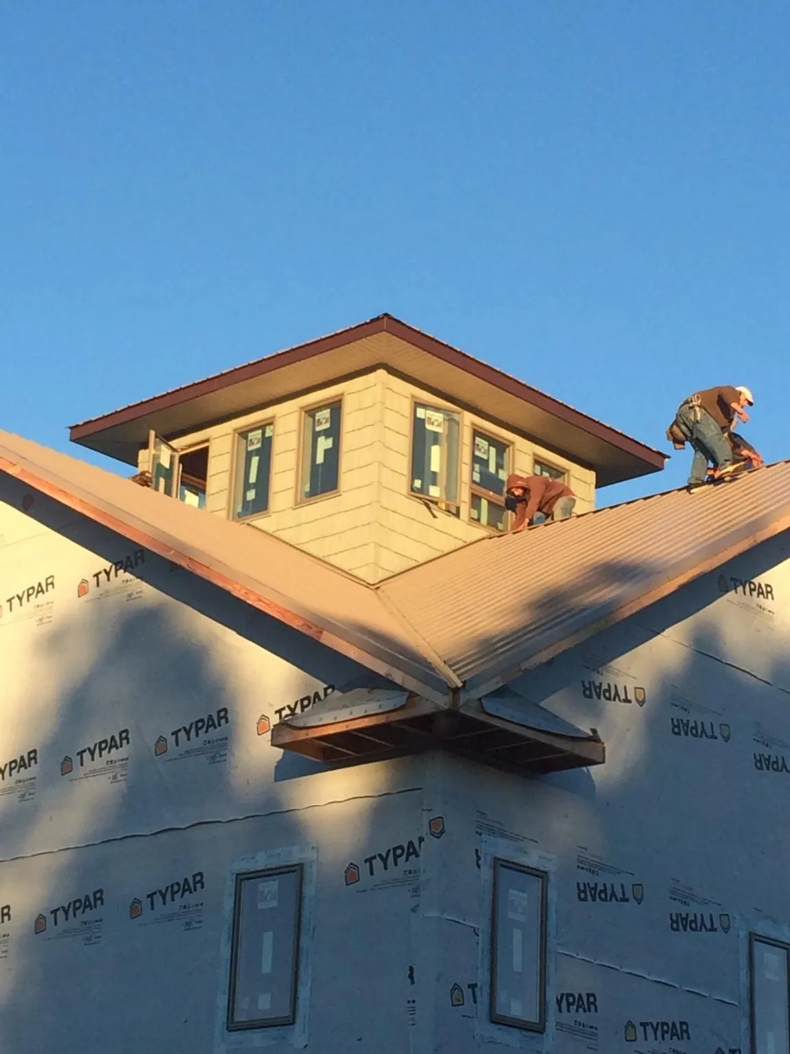Roofers working around a rooftop cupola on a new metal roof at sunset — Roof Waterproofing in Shoshone by Roofing Brothers